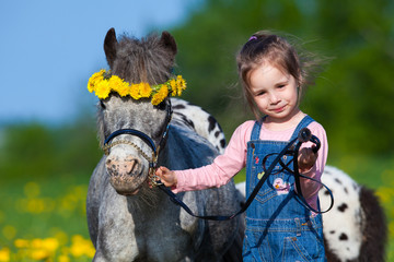 Child and small horse walking in field