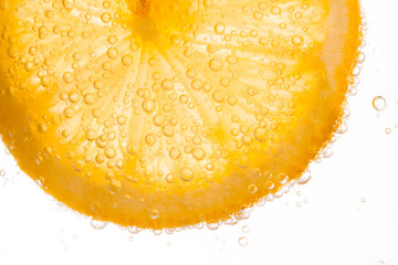 close-up of lemon slice in clear water with bubbles