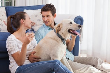 Couple with wine glass and pet dog in living room
