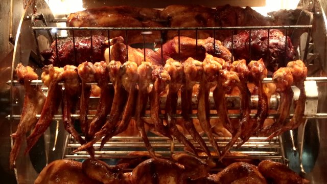 Куриные тушки и крылья жарятся на вращающемся гриле