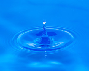 a drop of water falling in blue water. macro