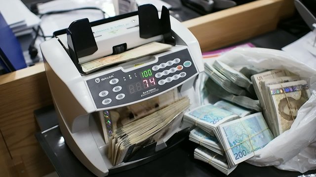 Teller machine counting Norwegian 500-bills from a plastic bag