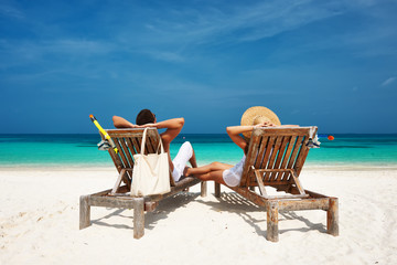 Fototapeta na wymiar Couple in white relax on a beach at Maldives