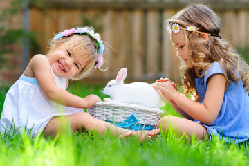 two little girl with a bunny rabbit has a easter at green grass