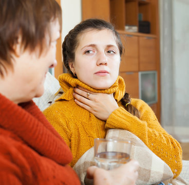 Woman giving glass of water to unwell friend
