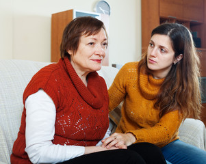 Adult daughter comforting sad mother at home