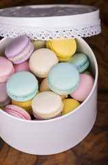Pastel color macaroons in vintage round box on a wooden