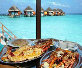 Two plates with lobster on table at window with view on ocean.. - 62253400