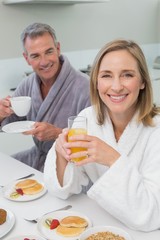 Obraz na płótnie Canvas Smiling couple with orange juice and coffee in kitchen
