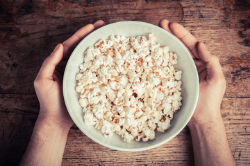 Hands holding a bowl of popcorn