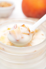 spoon of yogurt with honey, peaches and nuts close-up