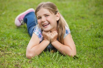 Happy young girl lying on grass at park
