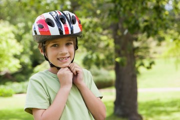 Fototapeta na wymiar Smiling boy wearing bicycle helmet at park