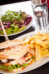 Clubsandwich auf getoastetem Weißbrot mit Speck und Pommes frit