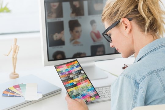Blonde designer looking at colour chart at her desk