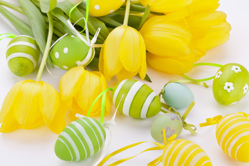 Farbenfrohe gelbe Tulpen mit grünen Blättern und Ostereiern zu