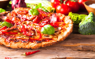 Pizza with fresh vegetable on wooden table.