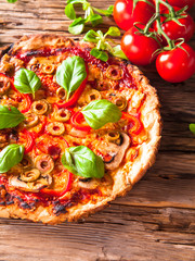 Pizza with fresh vegetable on wooden table.