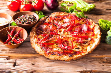 Pizza with fresh vegetable on wooden table.
