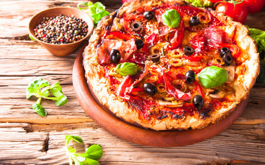 Pizza with fresh vegetable on wooden table.