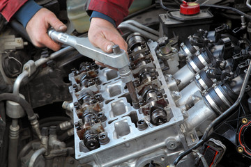 Mechanic fixing cylinder head with camshaft using socket wrench