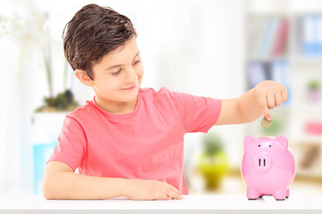 Boy inserting coins into a piggybank