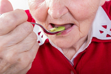 Alte Frau isst eine Kiwi