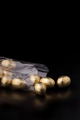 Obraz premium Chocolate mini eggs in a cellophane bag on a black background