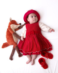Beautiful baby girl in red dress with fox