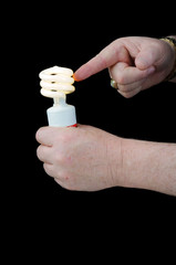 Man holding a pigtail flourescent light suggesting it is the way of the future to conserve power