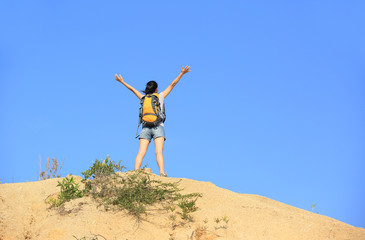  cheering woman hiker open arms at mountain peak