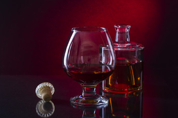Cognac bottle and glass on the red background.