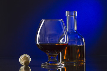 Cognac bottle and glass on the blue background.