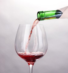 Pouring wine into wineglass isolated on white