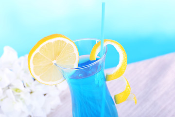 Glass of cocktail on table on light blue background
