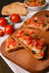 Delicious bruschetta with tomatoes on cutting board close-up