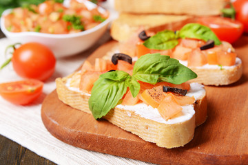 Delicious bruschetta with tomatoes on cutting board close-up