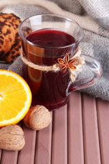 Mulled wine with orange and nuts on table on fabric background