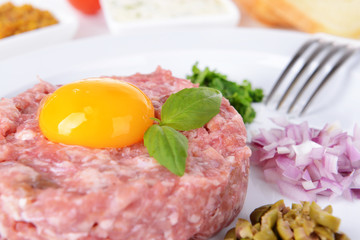 Delicious steak tartare with yolk on plate on table close-up