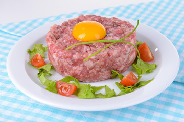 Delicious steak tartare with yolk on plate on table close-up