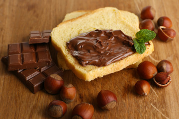 Bread with sweet chocolate hazelnut spread on wooden background