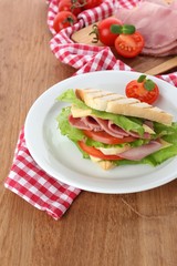 Tasty sandwich with ham on wooden table