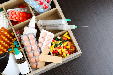 Medical pills, ampules in wooden box, on color wooden