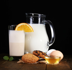 Eggnog with milk and eggs on table and black background