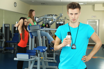 Young trainer and womans engaged in simulator in gym