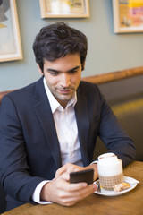 Handsome man using a cell phone in coffee