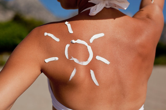 Tanning lotion in the shape of sun on woman's shoulder.