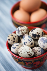 Close-up of raw quail and chicken eggs in khokhloma tableware