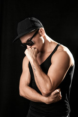 Fototapeta na wymiar Strong muscular man in sunglasses on black background