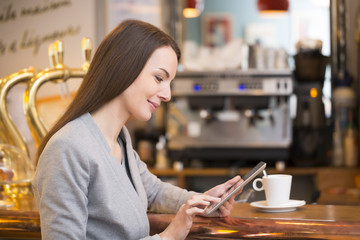 Beautiful young woman using her tablet pc in coffee bar